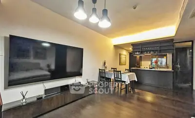 Modern living room with large TV and open kitchen layout, perfect for entertaining.