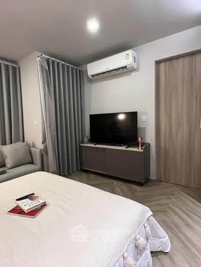 Modern bedroom with sleek design, featuring a cozy bed, stylish TV setup, and elegant curtains.