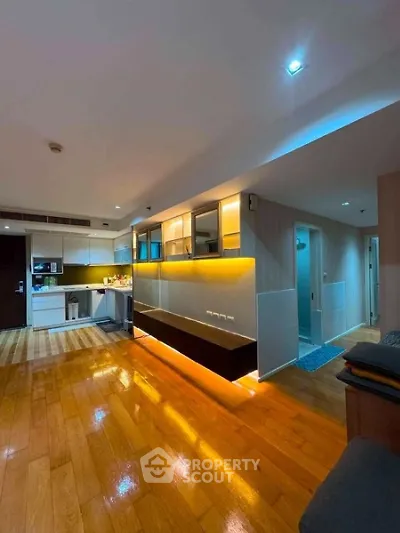Modern living room with wooden flooring and ambient lighting in a stylish apartment.