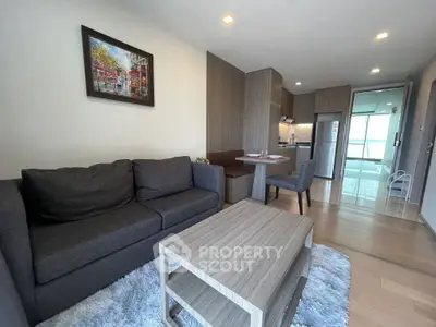 Modern living room with cozy seating and open kitchen layout in stylish apartment.