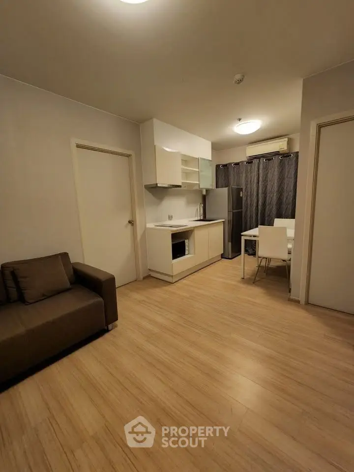 Modern apartment interior with open kitchen and cozy living area, featuring sleek design and wooden flooring.