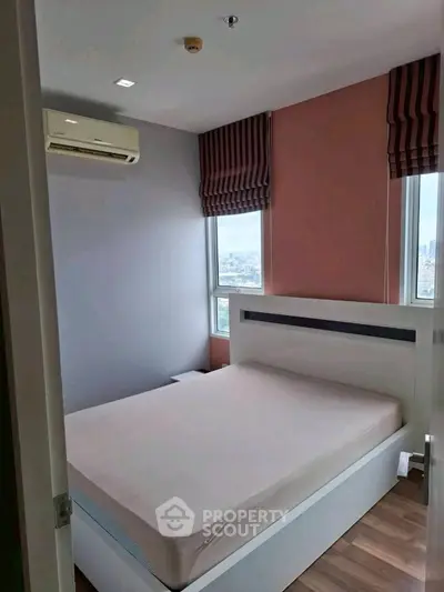 Modern bedroom with city view and air conditioning in high-rise apartment.