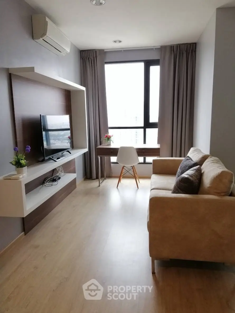 Modern living room with cozy sofa, TV, and large window view.