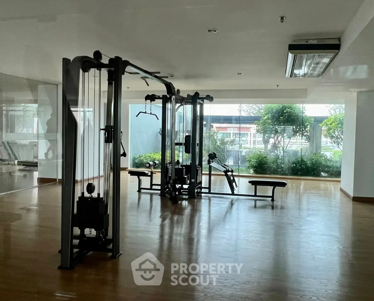 Spacious gym with modern equipment and large windows offering garden views.