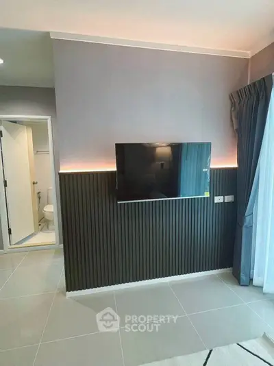 Modern living room with sleek TV setup and bathroom access, perfect for urban living.