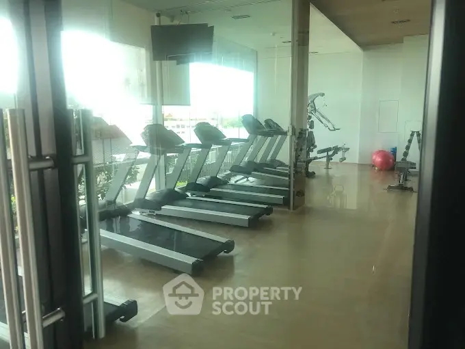 Spacious gym with modern equipment and large windows for natural light.