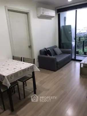 Modern living room with balcony view, featuring sleek furniture and natural light.