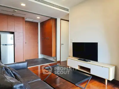 Modern living room with sleek furniture and flat-screen TV, showcasing contemporary design and wooden flooring.