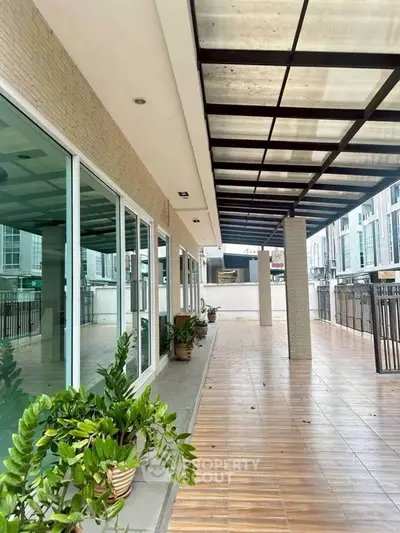 Spacious modern balcony with tiled flooring and glass doors in urban setting.