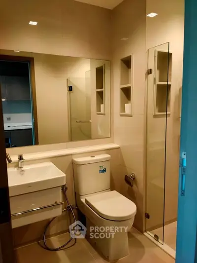 Modern bathroom with sleek fixtures and glass shower enclosure in a contemporary apartment.