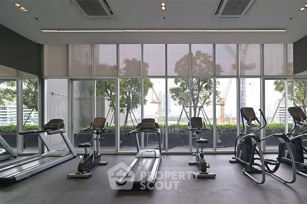 Modern gym with state-of-the-art equipment and large windows offering city views.