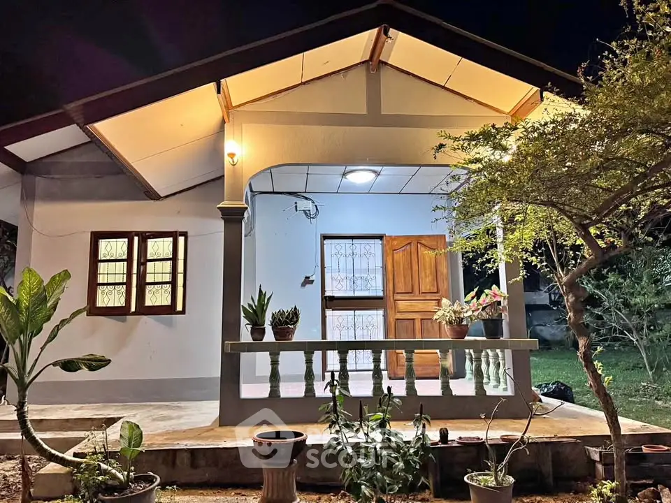 Charming single-story home with inviting porch and lush garden at night.