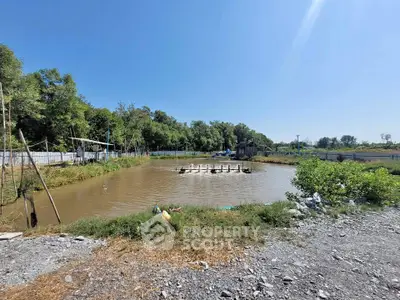 Scenic rural property with pond and lush greenery under clear blue sky.