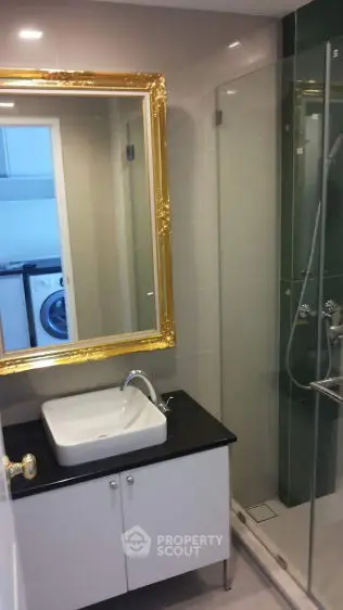 Modern bathroom with elegant gold-framed mirror and glass shower enclosure