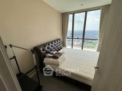 Cozy bedroom with stunning city view from large windows, featuring a comfortable bed and modern decor.