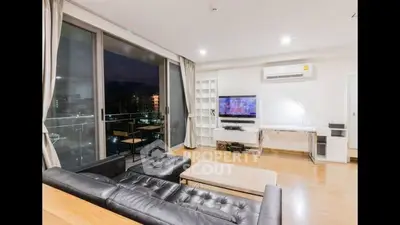 Spacious living room with modern furniture, large windows offering city views, and a sleek design, perfect for urban living.