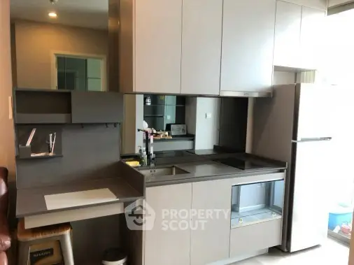 Modern compact kitchen with sleek cabinetry and integrated appliances in a stylish apartment.