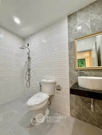 Modern bathroom with sleek design, featuring a shower, toilet, and stylish sink area.