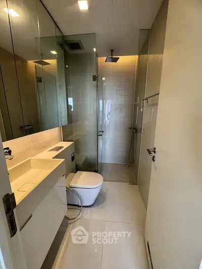 Modern bathroom with glass shower and sleek fixtures in a contemporary apartment.