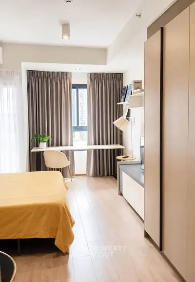 Modern bedroom with study area, large window, and stylish decor in a cozy apartment.
