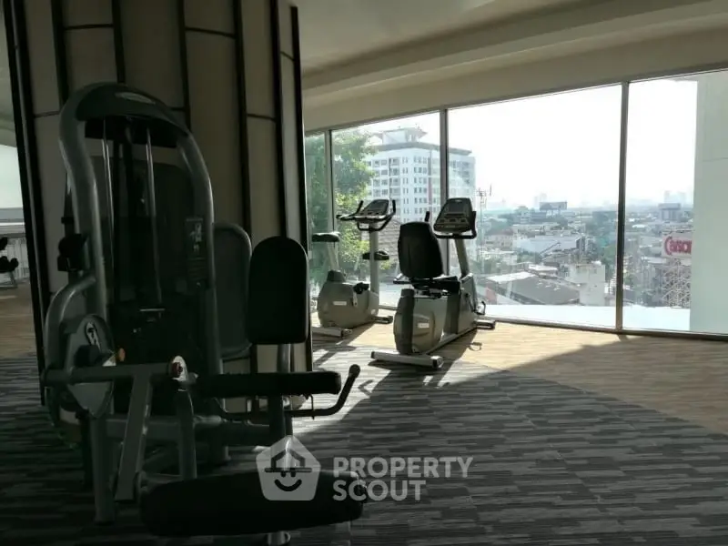 Spacious gym with modern equipment and panoramic city view.