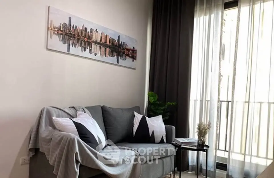 Modern living room with stylish sofa and cityscape artwork, featuring natural light from large windows.