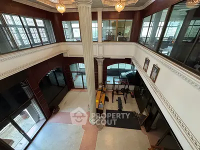Spacious two-story interior with elegant columns and large windows, ideal for luxury living or commercial use.