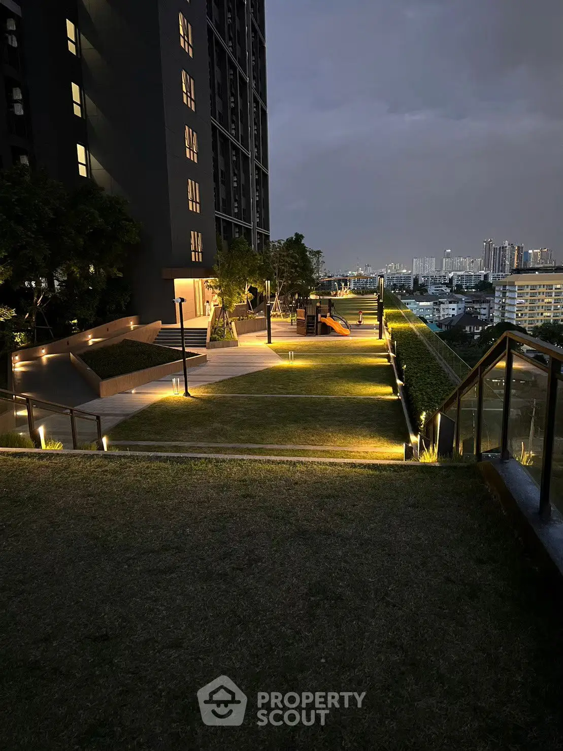 Stunning rooftop garden with city skyline view at dusk, featuring modern lighting and lush greenery.