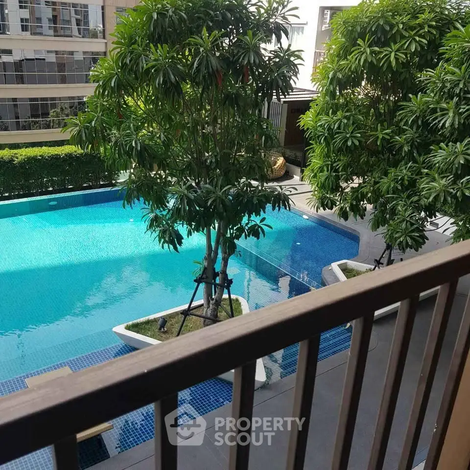 Luxurious poolside view from balcony with lush greenery in modern apartment complex.
