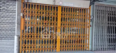 Secure commercial property with orange folding gate in urban setting.