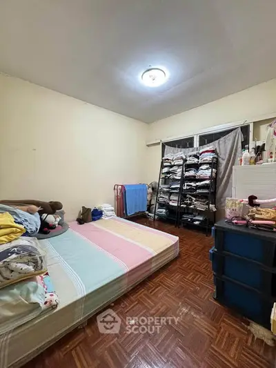 Cozy bedroom with parquet flooring and ample storage space, perfect for comfortable living.