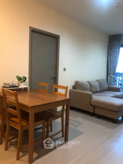 Cozy living room with wooden dining set and comfortable sofa, perfect for relaxation and entertaining.
