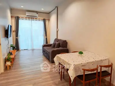 Cozy living room with modern decor and dining area, featuring natural light and wooden flooring.