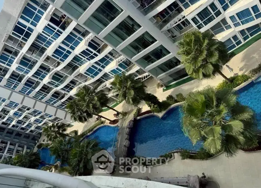 Luxurious apartment complex with stunning pool and palm trees view.