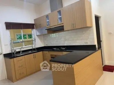 Modern kitchen with sleek wooden cabinets, black countertops, and a gas stove, featuring a bright and airy design.