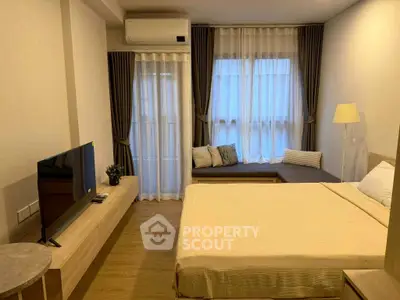 Modern bedroom with cozy decor and natural light, featuring a TV and stylish furniture.