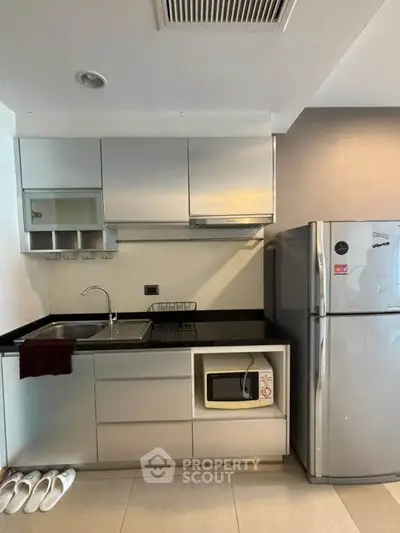 Modern kitchen with sleek cabinetry, stainless steel fridge, and built-in microwave.