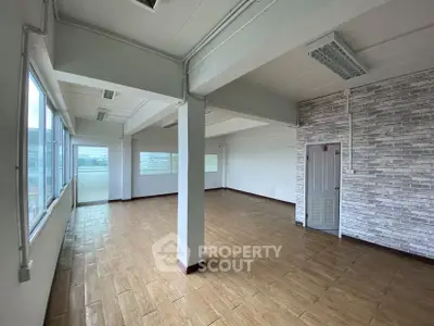 Spacious open-plan room with large windows and modern flooring, ideal for versatile use.