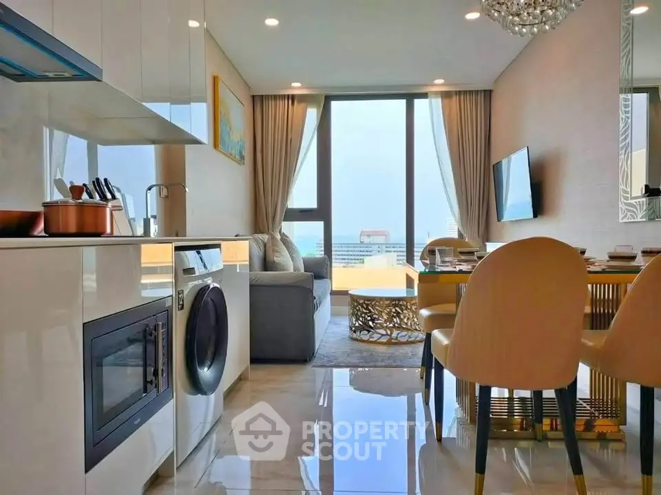 Modern open-layout living room with kitchen, featuring washing machine and elegant decor.