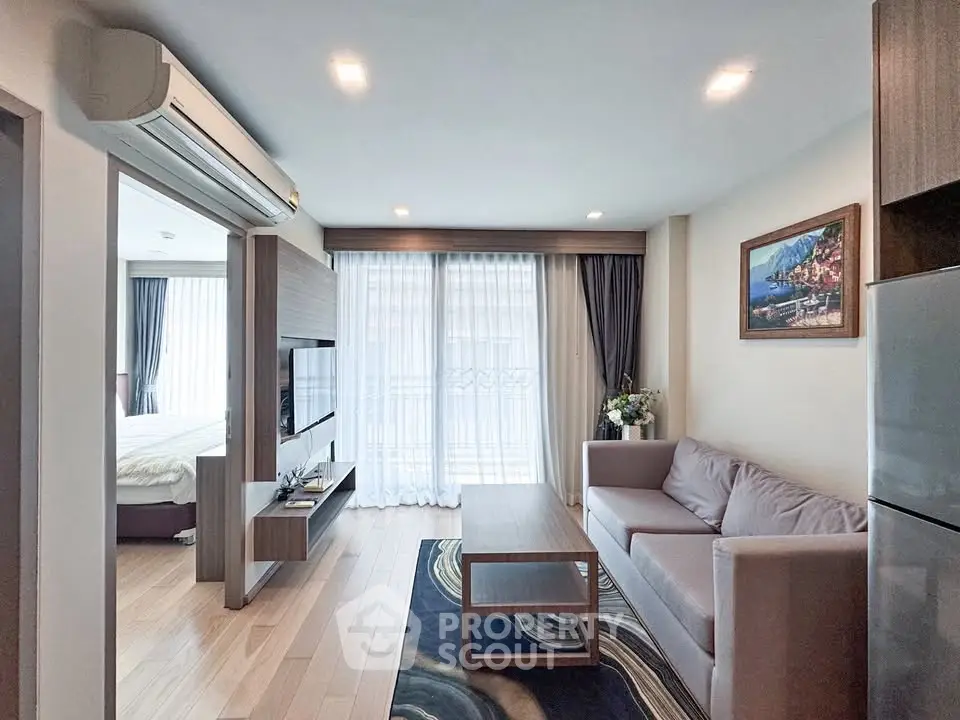 Modern living room with stylish decor and natural light, featuring a cozy sofa and wall-mounted TV.