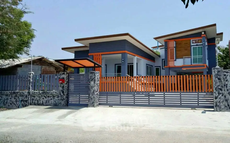 Modern two-story house with unique architectural design and vibrant orange accents.