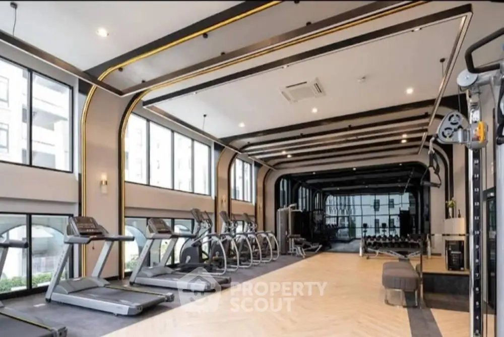 Luxurious modern gym with state-of-the-art equipment and large windows for natural light.
