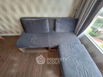 Cozy corner sofa with striped wallpaper and large window view