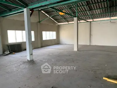 Spacious industrial warehouse interior with high ceilings and ample natural light.