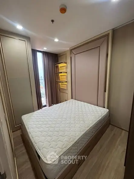 Cozy bedroom with modern design and large window offering city views.