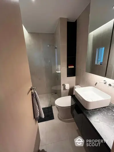 Modern bathroom with sleek design, featuring a stylish sink and glass shower enclosure.