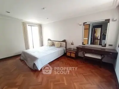 Spacious bedroom with elegant wooden flooring and natural light