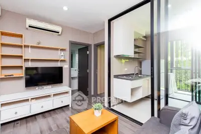 Modern living room with open kitchen and balcony view, featuring sleek furniture and natural light.
