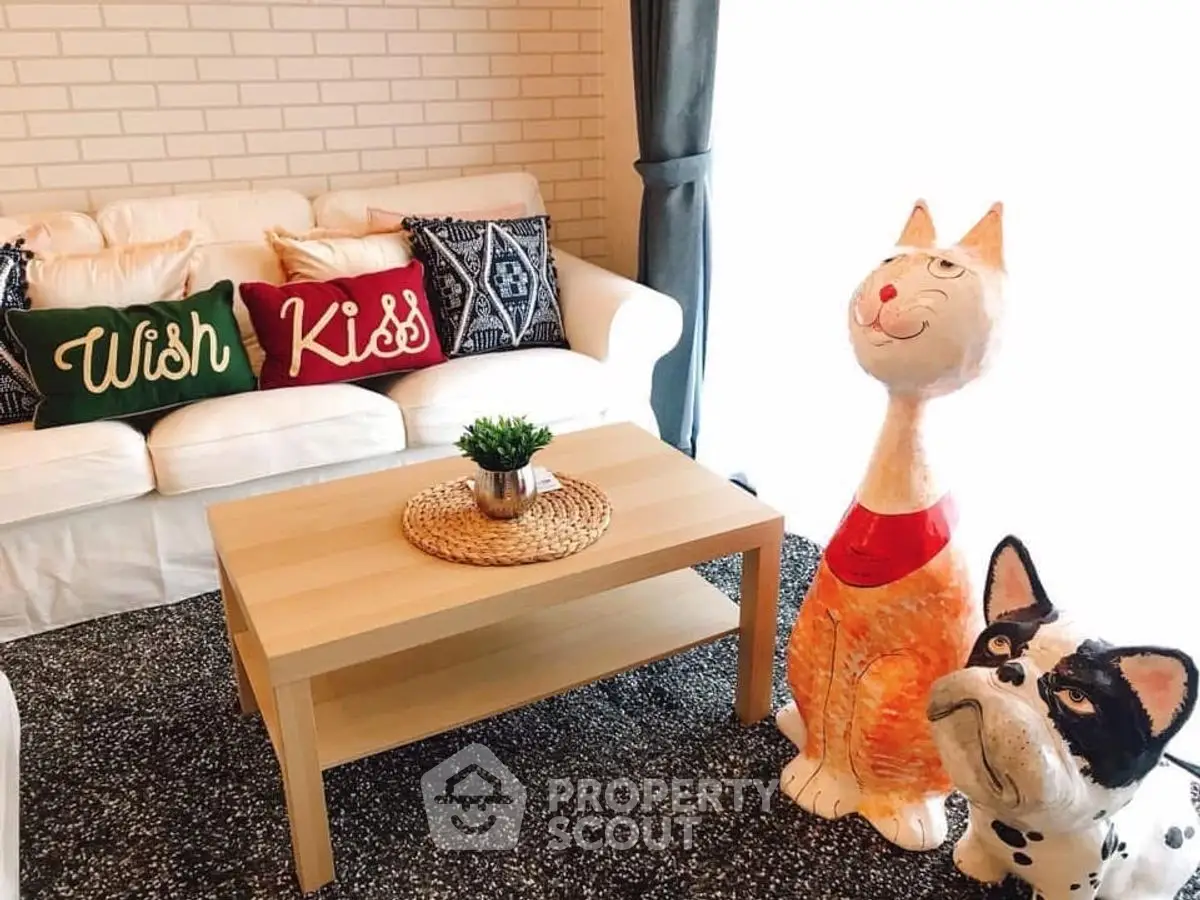 Charming living room with cozy sofa, playful cat and dog sculptures, and stylish decor accents.