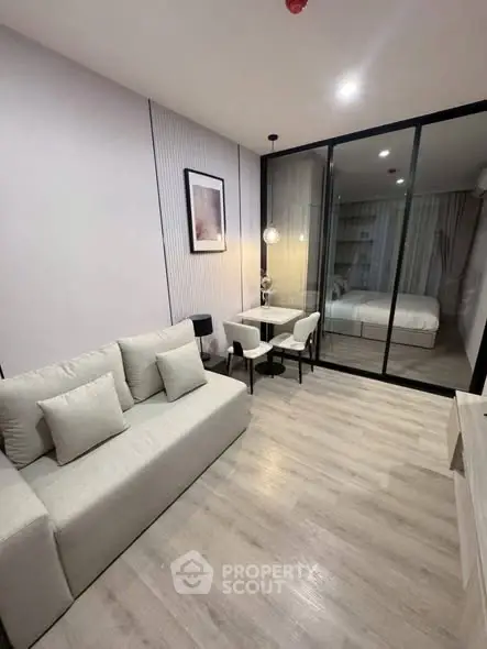 Modern living room with sleek design and glass partition leading to bedroom, perfect for urban living.